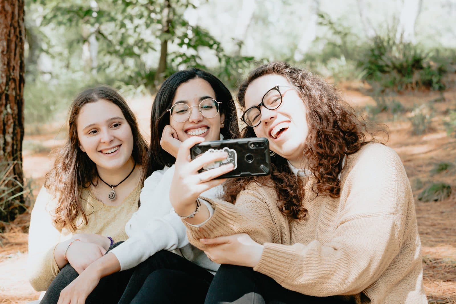 Trois amies rient en regardant le même téléphone