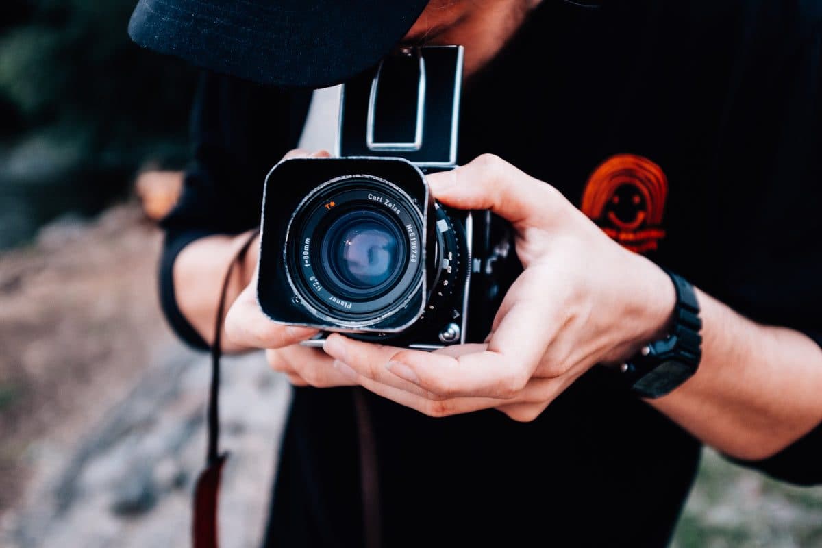 Un photographe tient son appareil à deux mains