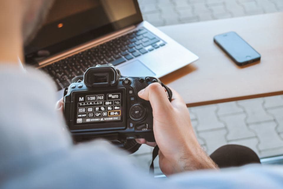 Un photographe règle son appareil, l’écran des réglages est allumé