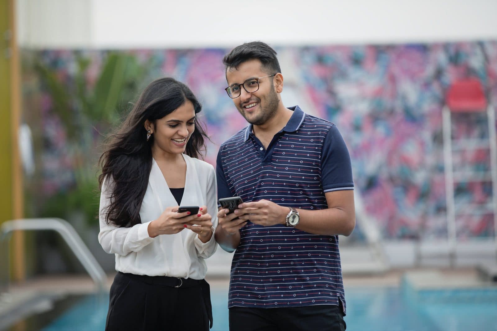 Deux invités sourient en regardant leurs téléphones