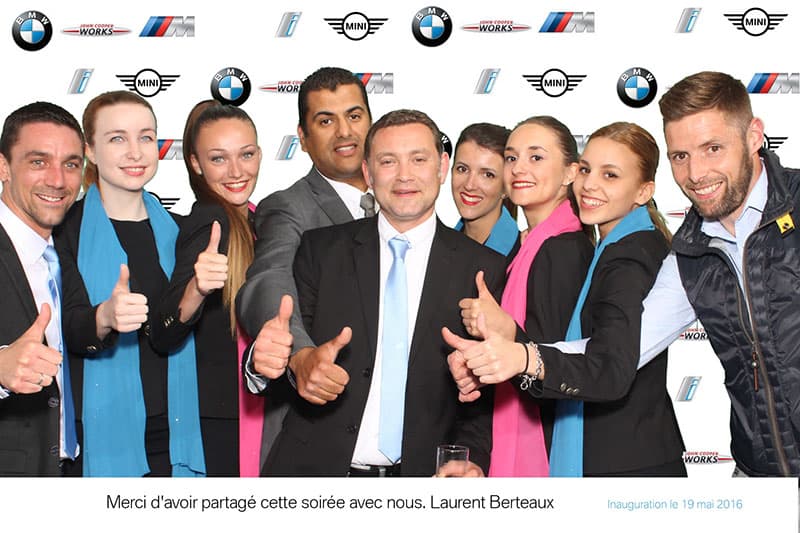 Groupe souriant pouce levé devant le photocall BMW MINI lors d'une inauguration